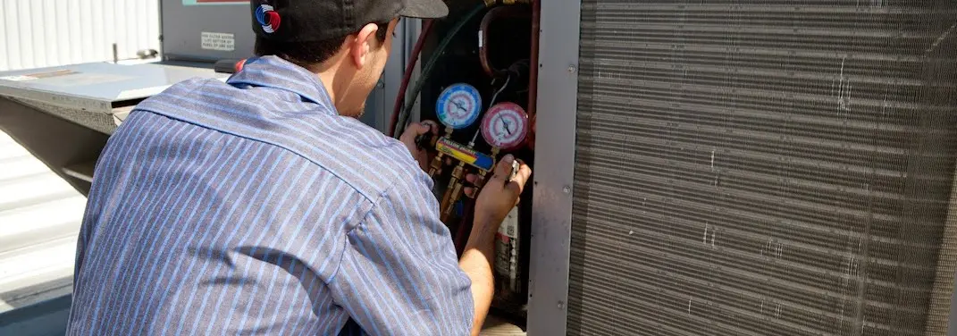 HVAC technician servicing a condenser unit in Huntington